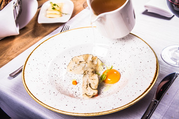 Broth with dumplings and an egg yolk being poured from a jug