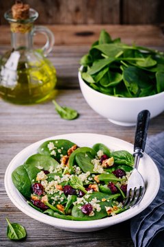 Green salad bowl with spinach, quinoa, walnuts and dried cranberries