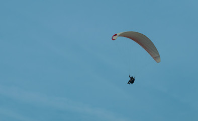 A man is flying on a parachute in the sky