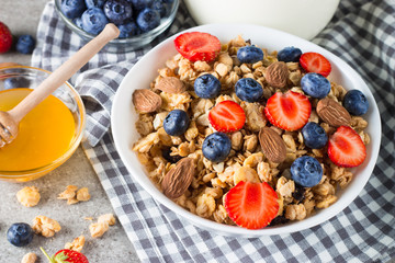 Healthy breakfast concept with oat flakes and fresh berries on rustic background. Food made of granola, muesli. Healthy banana smoothie with blackberries, muslie, strawberries, blueberries and honey.