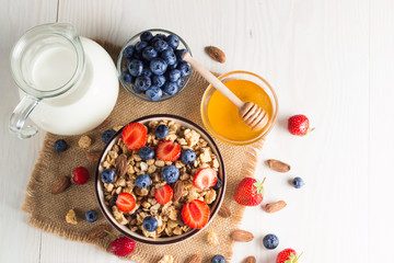 Healthy breakfast concept with oat flakes and fresh berries on rustic background. Food made of granola, muesli. Healthy banana smoothie with blackberries, muslie, strawberries, blueberries and honey.