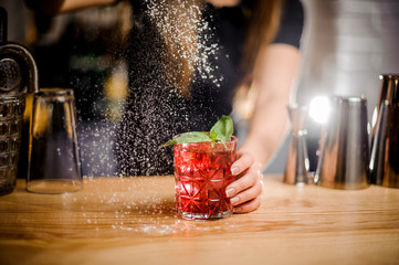 barmaid finishes cocktail preparation by adding a bitter of powdered sugar - obrazy, fototapety, plakaty