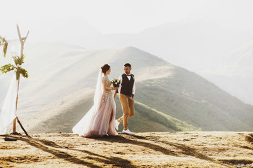 Bride and groom look lovely during the wedding ceremony on the top of the mountain somewhere in...