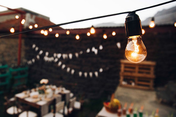 Yellow lamp hangs over dinner tables outside