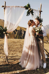 Bride and groom look lovely during the wedding ceremony on the top of the mountain somewhere in...