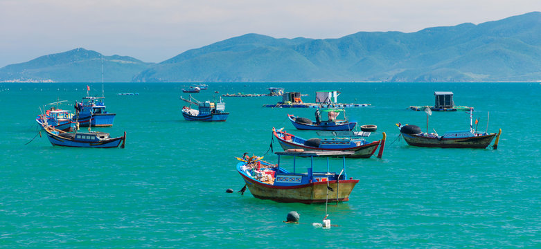Vietnamese coastline looking out over the south china sea in Nha Trang Vietnam with a turquoise ocean and fishing boats.