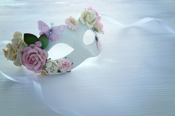 Image of delicate blue elegant venetian mask over wooden white background.