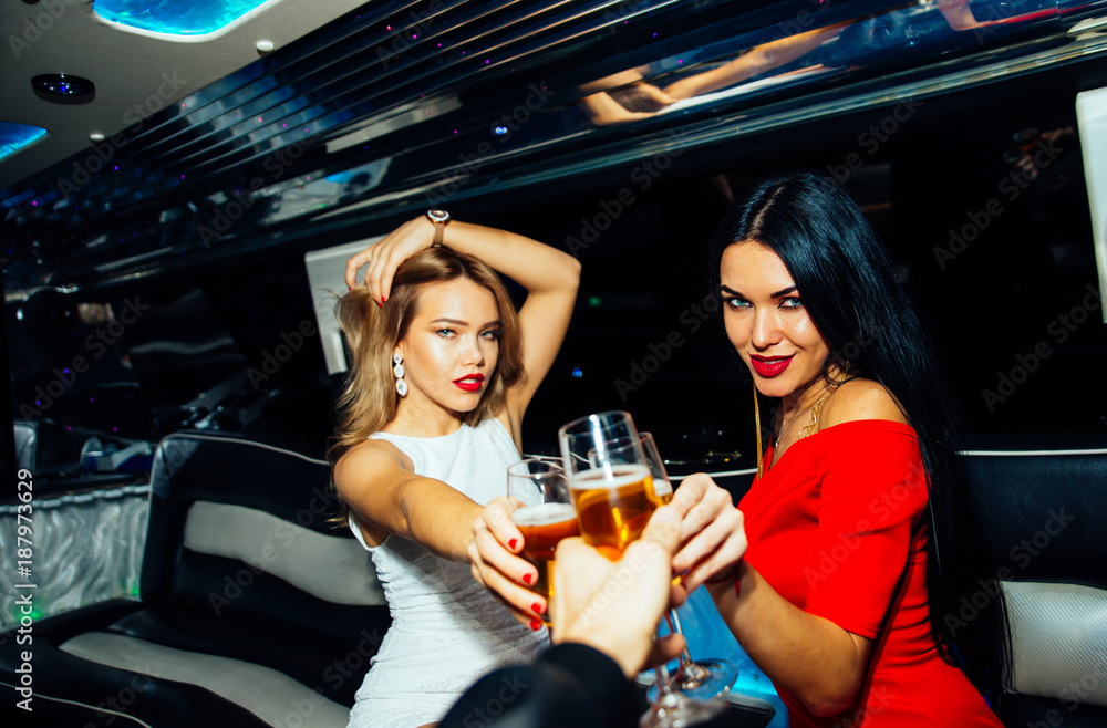 Wall mural Beautiful girls making party in the limousine