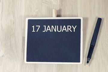 sentence JAN 17 written with chalkboard on a wooden table with pen.