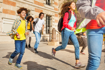 Group of mixed race teens running after classes