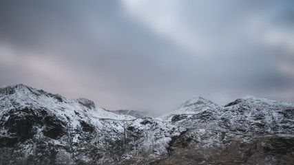 Beautiful Winter landscape image of Snowdonia National Park with snow capped mountains in background