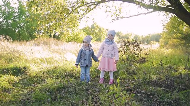 little boy and girl playing with white dog at sunset outdoors