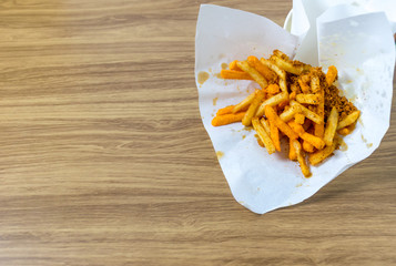 french fries In white paper wrap on wooden floor.