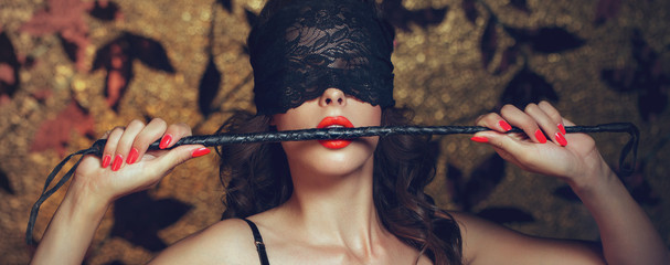Sexy Frau mit Augenbinde beißt Peitsche mit rotem Lippenbanner
