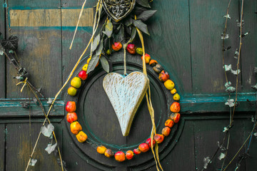 A pendant made of a wooden heart and dried apples as a symbol of love and an ecological way of life is suspended on the front door.