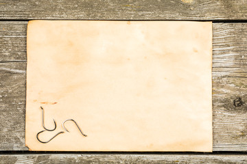 Fishing tackle - fishing, hooks, old sheet of paper on a wooden background