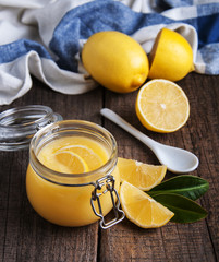 Lemon curd in glass jar with fresh lemons