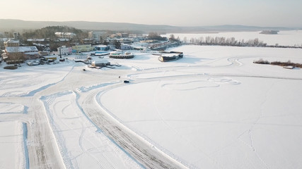 One car driving through the winter forest on country road. Top view from drone. Aerial view of snow covered road in winter, car passing by. Top view of the car traveling on snowy road