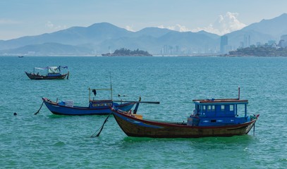 Naklejka na ściany i meble Vietnamese coastline looking out over the south china sea in Nha Trang Vietnam with a turquoise ocean and fishing boats.