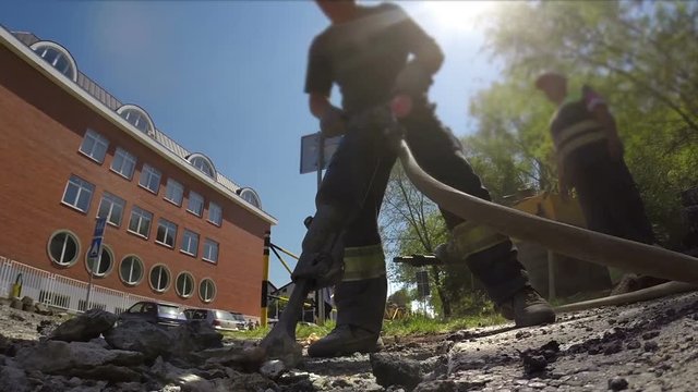 Roadworks construction workers using a jackhammer to break pavement and concrete