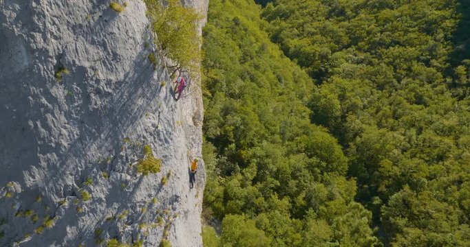 Total aerial view of friends rock climbing in amazing valley in the summer.
