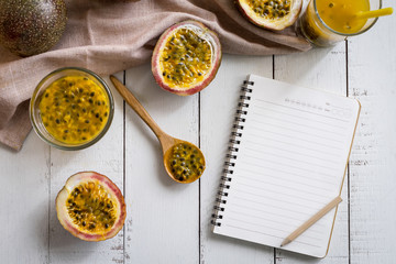 Passion fruit and empty notepad on white wooden background