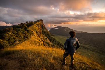 Young traveler looking at beautiful sunrise over the mountain