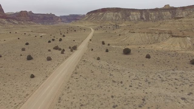 Aerial view flying over dirt road in the Utah desert leading through the San Rafael Swell.