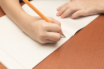 Obraz na płótnie Canvas The hand of a schoolgirl writes a pencil in notebook