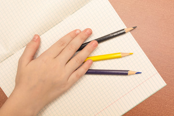 The hand of a schoolgirl holding colored pencils