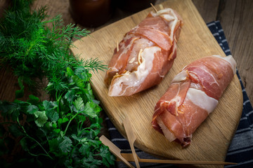 Raw chicken breast stuffed with champignon wrapped with bacon.