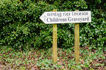 Direction sign to an Children's Graveyard in Ireland, in English and Irish Gaelic