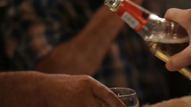 Man pouring alcohol in glasses of guests at party, hospitality and friendship