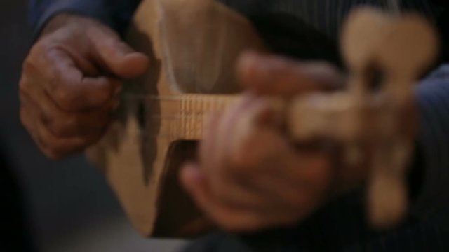 Old man playing wooden Georgian string music instrument, folk culture concert
