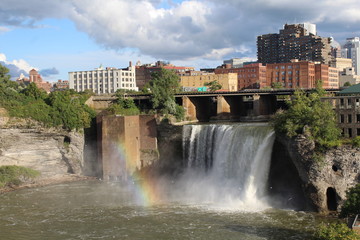 High Falls at Rochester, New York. Rainbow at base of the falls and city skyline in autumn