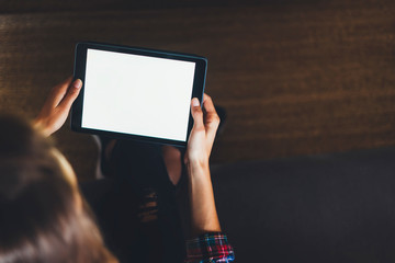 Naklejka premium Hipster girl using tablet technology in home, girl person holding computer with blank screen on background bokeh, female hands texting on relax holiday, mockup templates gadget