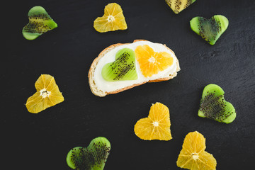 Sandwich with cream and citrus with kiwi fruit on black table. Natural food. Flat lay, top view