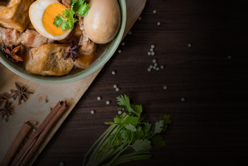 Pha-lo with dim light : Eggs boiled and pork boiled with spices and fried tofu in sweet gravy soup on wooden background with copy space © metha275