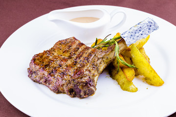 Grilled pork chop and baked potatoes on white plate