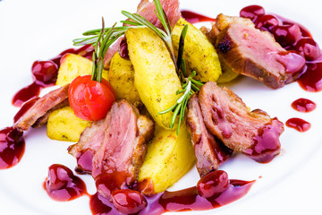 Duck breast with berry sauce and baked potato on white plate