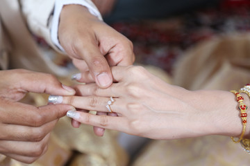 Thai groom wearing wedding ring for his bride