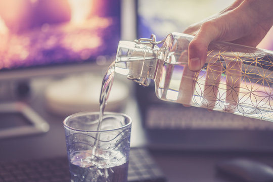Wasser wird aus Flasche in Glas eingeschenkt, Arbeitsplatz