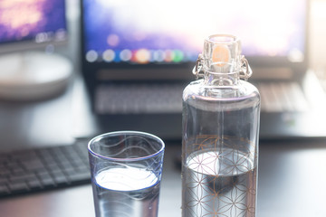 Wasserflasche und Wasserglas am Arbeitsplatz, trinken