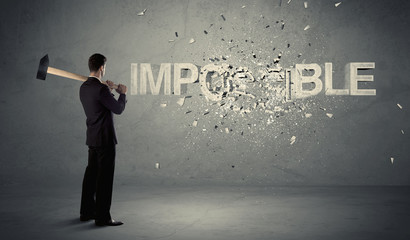 Obraz premium Business man hitting impossible sign with hammer