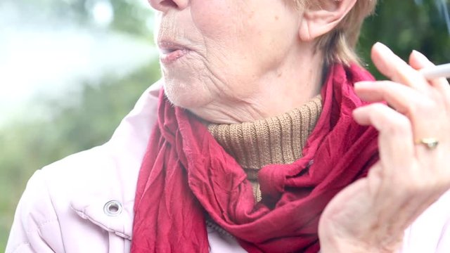 Cinemagraph of older woman standing outdoors and smoking a cigarette
