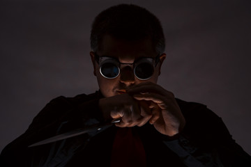 A man is posing with a knife. In safety glasses. Crime.