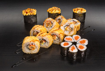 Sushi and roll set with seafood isolated on black wood background with reflection. Japanese cuisine.
