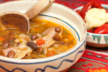 bowl with delicious bean soup with smoked meat and assorted pickles aside