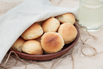 Homemade freshly baked buns in a clay plate and a glass of fresh kvass. Delicious bread