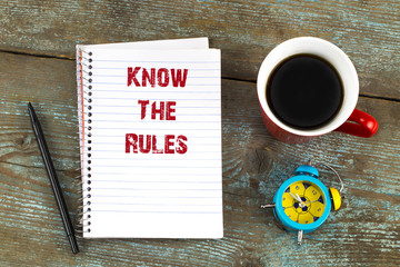  know the rules- text on notepad with, cup of coffee on wooden desk. Top view